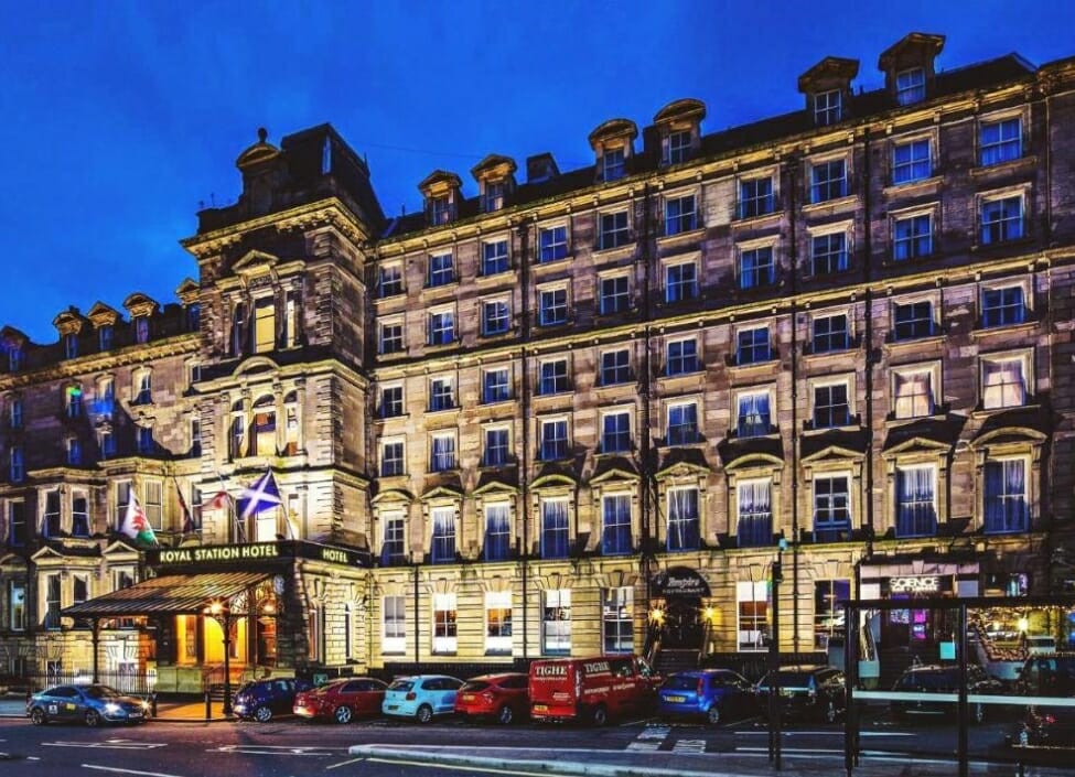 Royal Station Hotel near Newcastle Train Station lit up at night with cars parked in front